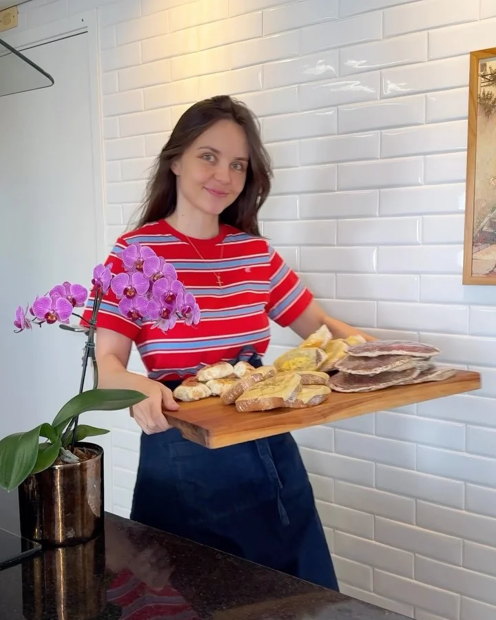 Tálita de camiseta listrada vermelha segurando uma tábua com preparos para a rotina